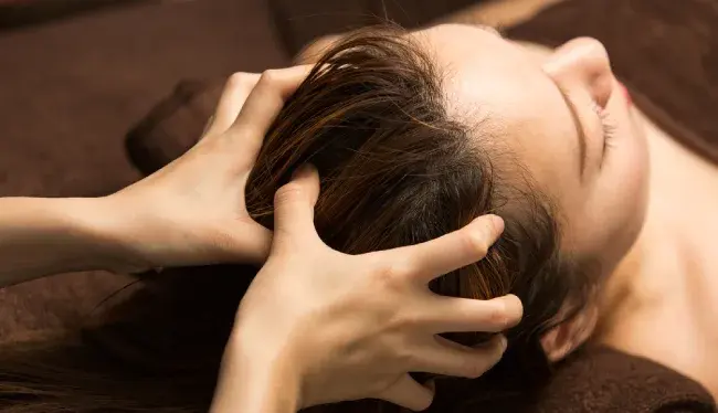 فردی در حال ماساژ دادن پوست سر یک زن