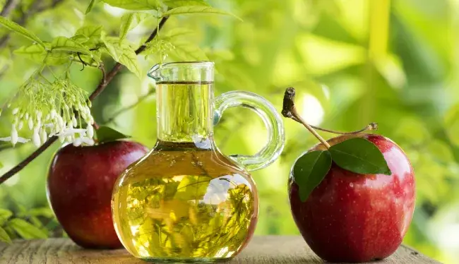 دو سیب در کنار یک ظرف سرکه سیب