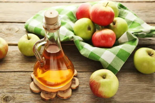 چند سیب در کنار یک ظرف سرکه سیب