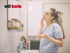 زنی در حال انجام روتین پوستی جلوی آیینه در حمام