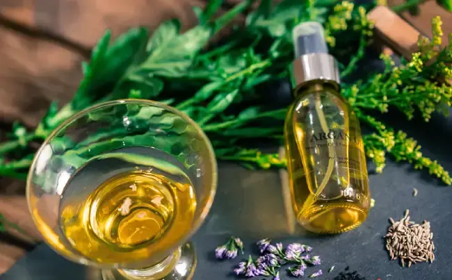 یک قوطی روغن آرگان در کنار یک ظرف روغن آرگان