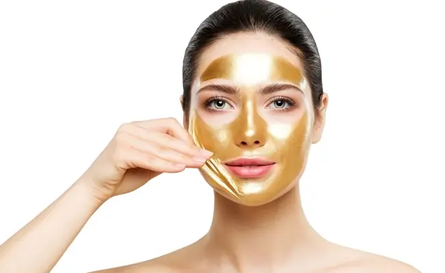 زنی در حال استفاده از فواید ماسک طلا روی پوست صورت خود