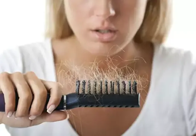 زنی شانه‌ای پر مو در دست داشته و به علت گره خوردن مو فکر میکند